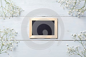 Framework for photo or congratulation on blue rustic wooden desk with flowers. Spring background, banner mockup for Womens or Moth