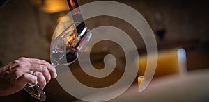 FRANCE, GIRONDE, SAINT-EMILION, SAMPLING A GLASS OF WINE IN A BARREL WITH A PIPETTE FOR TASTING AND VINIFICATION