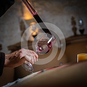 FRANCE, GIRONDE, SAINT-EMILION, SAMPLING A GLASS OF WINE IN A BARREL WITH A PIPETTE FOR TASTING AND VINIFICATION