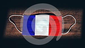 France National Flag at medical, surgical, protection mask on black wooden background. Coronavirus Covidâ€“19, Prevent infection,