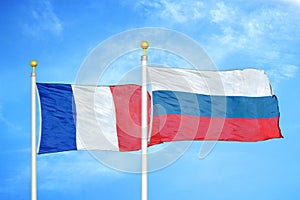 France and Russia two flags on flagpoles and blue cloudy sky