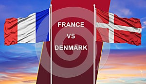 France vs. Denmark two flags on flagpoles and blue cloudy sky background.