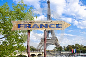 France wooden arrow road sign against Eiffel tower during spring background. Travel to France concept