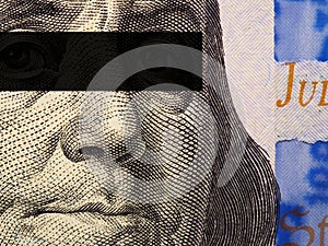 Franklin`s face close-up with a black stripe of censorship on his eyes on a fragment of a 100 dollar bill of the new sample.