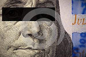 Franklin`s face close-up with a black stripe of censorship on his eyes on a fragment of a 100 dollar bill of the new sample.