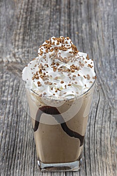 Frappuccino with ice in take away cup, with straws and grains of coffee on a wooden table, copy space