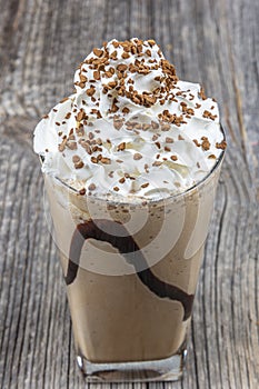 Frappuccino with ice in take away cup, with straws and grains of coffee on a wooden table, copy space