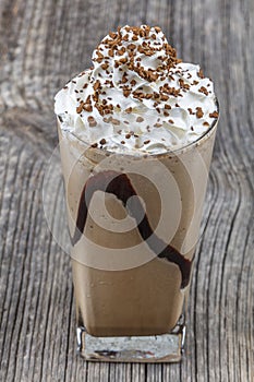 Frappuccino with ice in take away cup, with straws and grains of coffee on a wooden table, copy space