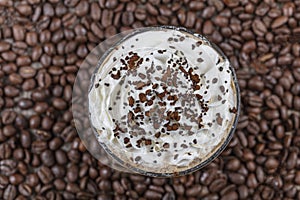 Frappuccino with ice in take away cup, with straws and grains of coffee on a wooden table, copy space