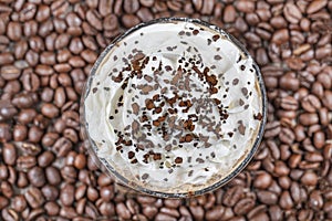 Frappuccino with ice in take away cup, with straws and grains of coffee on a wooden table, copy space