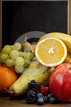 Frash Fruit, Orange, apple, banana, pear, grapes against blackboard