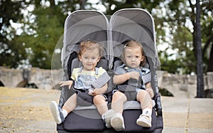 Fraternal twin baby girls sitting in stroller, baby carriage