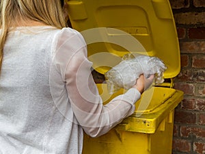 Frau wirft etwas in gelbe Tonne photo