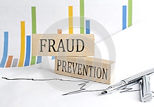 FRAUD PREVENTION text on a wooden block on chart background , business concept