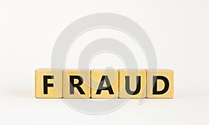 Fraud symbol. The concept word `fraud` on wooden cubes on a beautiful white table. White background. Business and fraud concept