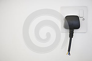 Frayed electrical cord with outlet attached on white wall