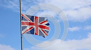 frayed English flag at half mast ruined due to bad weather