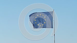 Frayed European Union flag is fluttered by a strong wind, blue sky background