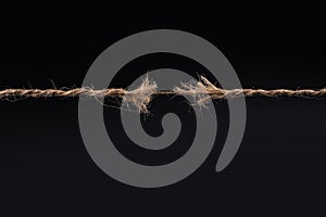 Frayed rope ready to break isolated on black background