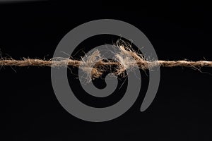 Frayed rope ready to break isolated on black background