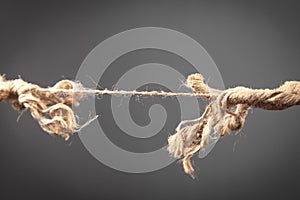 Frayed rope about to break on grey background. Risk