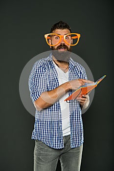Freak and geek. Bearded man in party glasses reading book. Study nerd holding lesson book. University male student with