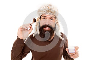 Freak visagiste. Applying makeup face tone. Powder cosmetics. Man bearded fashion stylist wear hat hold brush for