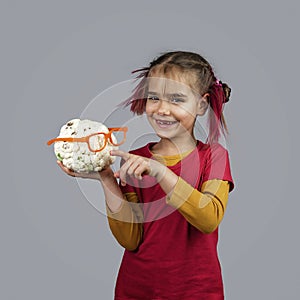 Freakish kid holds misshapen wrong color fruits and vegetables, waste food concept