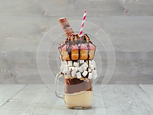 Freakshake with donuts on gray wooden background
