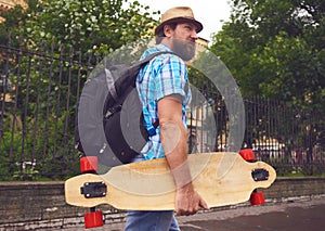 Freaky bearded man walking with longboard