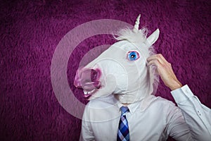 Freaky young man in comical mask stands on the purple background