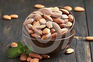 Freash almond in bowl on dark wooden kithcen table background, selective focus