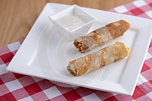 Frech crepes, two savoury pancakes made with flour and milk served with sour cream on a plaid background.