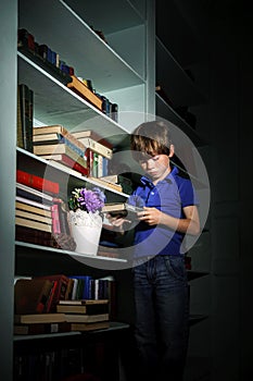 Freckled red-haired little boy searching book on bookcase