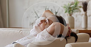 Freckled woman relaxing leaned on sofa with hands behind head