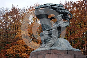 Frederic Chopin statue monument in Lazienki Royal Baths Park in Warsaw, Poland in autumn with foilage on the trees