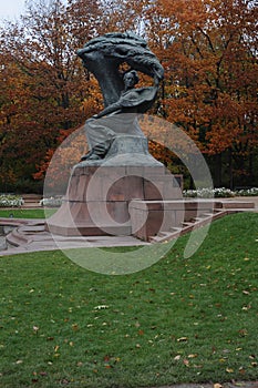 Frederic Chopin statue monument in Lazienki Royal Baths Park in Warsaw, Poland in autumn with foilage on the trees