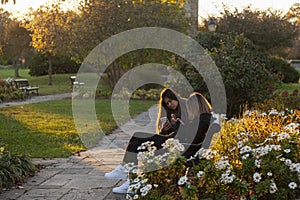 Two teenager girls are sitting on a bench in Baker Park at sunset