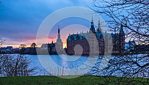 Frederiksborg castle on the sunset, with lake and tree in the foreground, Hillerod