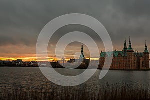 Frederiksborg castle on the sunset, with lake and tree in the foreground, Hillerod, Denmark