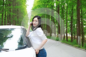 Free carelss happy woman stand by a white car on a road in forest