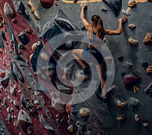 Free climber female bouldering indoors.