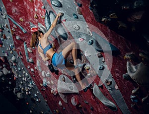 Free climber female bouldering indoors.