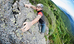 A free-climber reaches the top of a rocky wall. Concept: courage