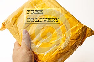 FREE DELIVERY text on yellow parcel package or cargo box with product in male hand, free logistic shipping and distribution