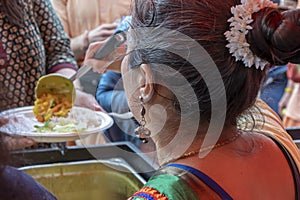 Free distribution of food and treats at a Hindu festival, vegetarian meals for passersby, feeding lit food to people.