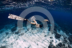 Freediver with fins glides underwater with turtle in ocean. Snorkeling with sea turtle