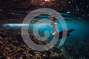 Free diver woman with fins over coral bottom. Freediving underwater in ocean