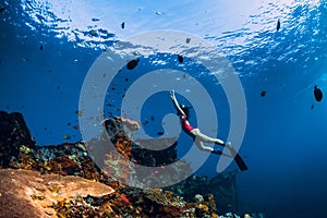 Free diver woman swimming with fins at wreck ship. Freediving in ocean over corals