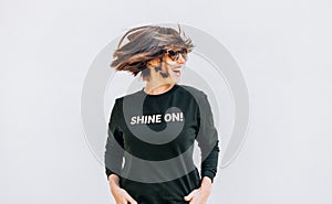 Free feeling happy smiling woman posing in black sweatshirt with positive print Shine On. She rotating a head bacause a cheerful